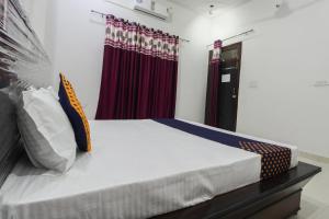 a bed in a room with red curtains at SPOT ON Green Valley in Meerut