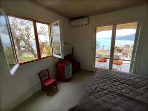 a bedroom with windows and a bed and a red chair at Lilly's Seaview Retreat Cottage in Avlákia