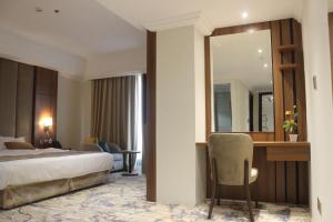 een slaapkamer met een bed, een bureau en een spiegel bij Hola Hotel in Al Jubail