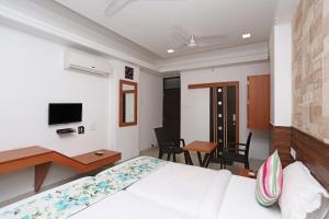 a bedroom with a bed and a desk and a tv at OYO Hotel Grand Nishat in Patna