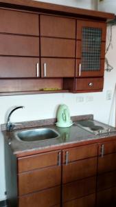a kitchen counter with a sink and wooden cabinets at Relax Unit In Porto Sharm Resort in Sharm El Sheikh