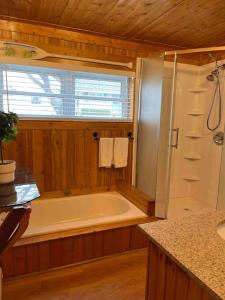 een badkamer met een bad en een raam bij Cozy Grand Bend Cottage with Bunkie in Grand Bend