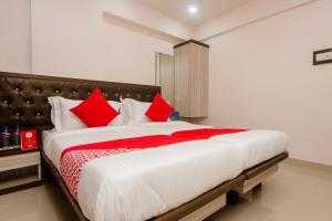 - une chambre avec un grand lit et des oreillers rouges dans l'établissement OYO Hotel Gems, à Turambhe