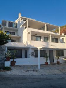 un bâtiment blanc avec des plantes en pot devant lui dans l'établissement İlya Apart 2, à Bodrum City