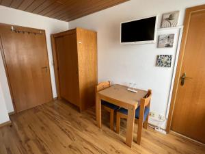 Habitación pequeña con mesa y TV en la pared. en Pension Seliger, en Meersburg