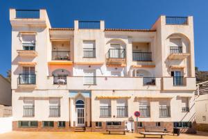 a building with balconies and a bench in front of it at Apartamento junto al mar en costa tropical y Alpujarras granadinas in Melicena