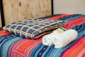 a pile of towels and a pillow on a bed at Rainbow House Ha Giang in Ha Giang