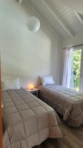 2 camas en una habitación con ventana en Depto Lácar Suites en San Martín de los Andes