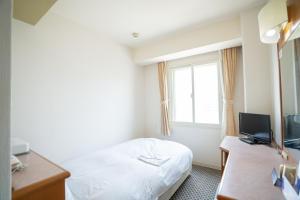 神戸市にあるホテルカサベライン神戸のベッドと窓が備わるホテルルーム
