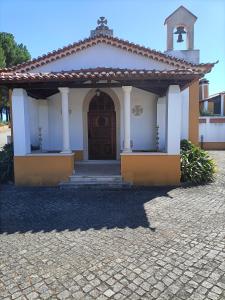 un piccolo edificio bianco con una porta e un campanile di Family House Cup- Quinta das Pinheirinhas a Tomar