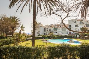 un complejo con piscina y palmeras en Sunny Beach Apartment, en Estepona