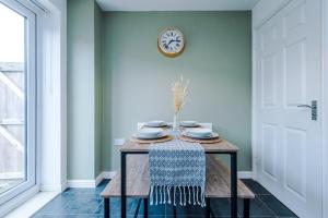 una mesa en una habitación con un reloj en la pared en Chic 2 Bed House with Garden & Free Parking, en Mánchester