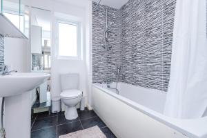 a bathroom with a toilet and a tub and a sink at Chic 2 Bed House with Garden & Free Parking in Manchester