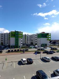un aparcamiento con coches estacionados frente a un gran edificio en Apartament Green Park 2 en Starogard Gdański