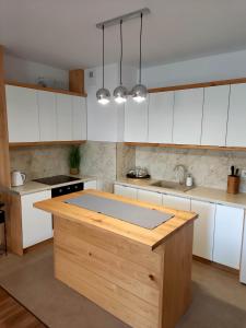 una cocina con armarios blancos y una isla de madera en Apartament Green Park 2, en Starogard Gdański