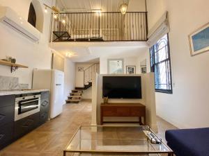 ein Wohnzimmer mit einem TV und einer Küche in der Unterkunft Kubler's House - By Beach Apartments TLV in Tel Aviv