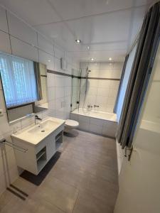 ein Badezimmer mit einem Waschbecken, einer Badewanne und einem WC in der Unterkunft Hotel-Gasthof Postbräu Dingolfing in Dingolfing