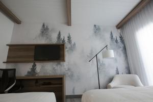 a bedroom with two beds and a tv on a wall at Hotelia in Saint-Ambroise