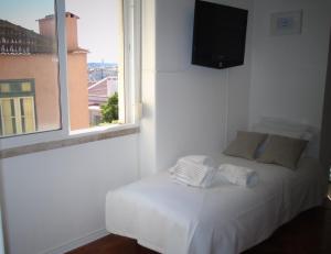 Bett in einem Zimmer mit Fenster und TV in der Unterkunft Graça River View in Lissabon