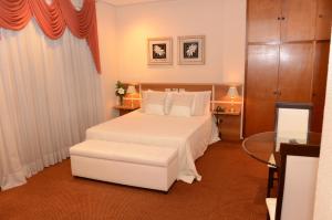 1 dormitorio con 1 cama blanca grande con almohadas blancas en Skalla Hotel Nova Odessa, en Nova Odessa