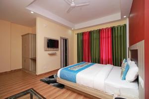 a bedroom with a bed with colorful curtains and a television at OYO Hotel Chandni in Dharmsāla