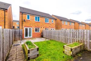 a backyard with a fence and some plants in boxes at Chic 2 Bed House with Garden & Free Parking in Manchester