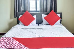 a red and white bed with two pillows on it at OYO Infinity Inn in Dhantoli