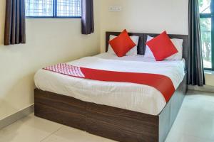a bed in a room with red pillows on it at OYO Infinity Inn in Dhantoli