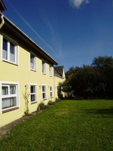 una casa amarilla con un césped verde delante de ella en Hotel garni Godenhof, en Wanderup