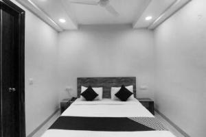 a white bedroom with a bed with black pillows at Flagship Comfort Residency Near Artemis Hospital in Gurgaon
