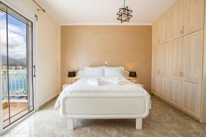 a bedroom with a white bed and a large window at Casa Jokaste in Karpathos