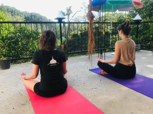 two women are sitting on a yoga mat at Noname Hostel And Cafe in Ella