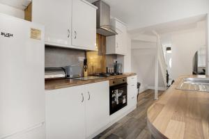 cocina con armarios blancos y suelo de madera en Freshly Renovated, Feels Like Home, Sleeps 3, en Chester-le-Street