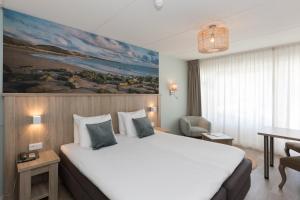 ein Hotelzimmer mit einem großen Bett und einem Schreibtisch in der Unterkunft Beach Hotel I Kloeg Collection in Zoutelande
