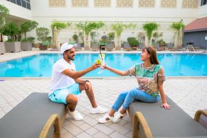 Ein Mann und eine Frau sitzen mit einem Drink auf Bänken in der Unterkunft Novotel World Trade Centre Dubai in Dubai