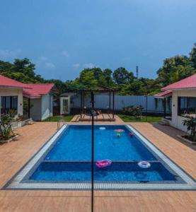 a swimming pool with an umbrella in a yard at Tiara Resort Mandwa in Alibaug
