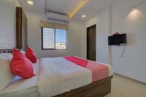 a bedroom with a bed with red pillows and a television at RK regency in Yerandwane