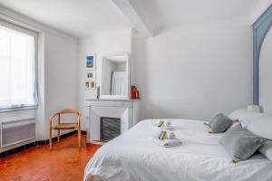 Maison Castel - Welkeys في تولون: غرفة نوم بيضاء مع سرير ومدفأة
