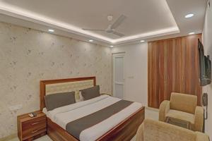 een slaapkamer met een bed en een stoel en een tv bij Super Collection O Hotel Spot Light Near Tughlakabad Station Metro Station in Indraprastha