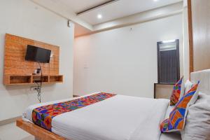 a bedroom with a bed and a tv on a wall at FabHotel Bliss Inn in Prayagraj