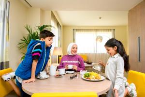 杜拜的住宿－迪拜世貿中心諾富特酒店，一群坐在桌子旁吃食物的孩子