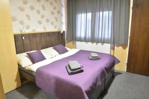 een slaapkamer met een paars bed met 2 handdoeken erop bij Penzion Klimeš in Hustopeče