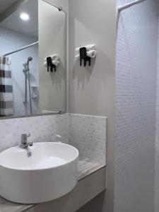 Baño blanco con lavabo y espejo en Cebu Mini Hotel, en Cebú
