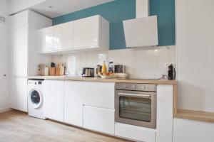 kuchnia z białymi szafkami, pralką i suszarką w obiekcie Loft L'Escale - 3 étoiles - Welkeys w mieście La Ciotat
