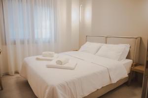 a white bed with two towels on top of it at Plataria Sunrise Resort in Plataria