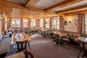 een restaurant met houten tafels, stoelen en ramen bij Riedbergerhorn - Gasthof & Ferienwohnungen in Bolsterlang