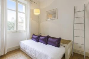 łóżko z fioletowymi poduszkami w pokoju z oknem w obiekcie Appartement Gardague - 2 étoiles - Welkeys w Biarritz