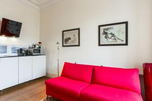 czerwona kanapa w salonie z białymi ścianami w obiekcie Appartement Gardague - 2 étoiles - Welkeys w Biarritz