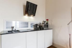 kuchnia z białymi szafkami i telewizorem na ścianie w obiekcie Appartement Gardague - 2 étoiles - Welkeys w Biarritz +4 zdjęcia