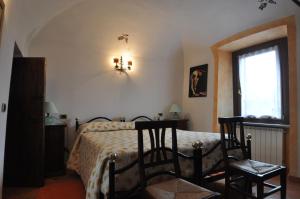 a bedroom with a bed with two chairs and a window at B&B Casa Camilla - Affitti Brevi Italia in Niella Tanaro